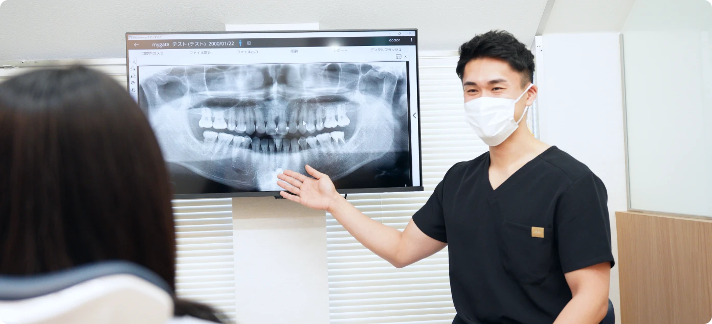 アンンサンブル歯科 青葉台の診療室で、歯科医師がモニターを使い治療説明を行う様子